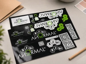 White vinyl sticker sheet with black logo designs on tabletop for business branding - Sticker Sheet Printing